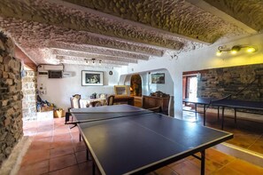 Une pièce avec une table de ping-pong, des murs en pierre et un plafond rustique.