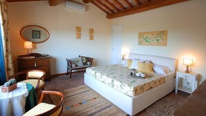 A bedroom with a bed, bedside tables, a dresser, a chair, a small table with a lamp, and a mirror on the wall. - Green House Near Civita di Bagnoregio - Amazing Panoramic View - Free Wi-fi (Bagnoregio)