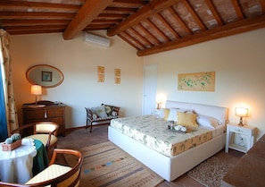 A bedroom with a bed, bedside tables, a dresser, a chair, a small table, and a mirror.