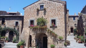 A stone building with arched doorways, a central staircase, and flower boxes on the windows. - Green House Near Civita di Bagnoregio - Amazing Panoramic View - Free Wi-fi (Bagnoregio)