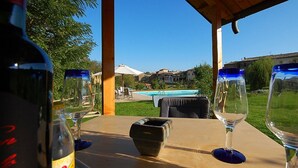 A table with two wine glasses and a bottle, a pool, and a view of a residential area. - Green House Near Civita di Bagnoregio - Amazing Panoramic View - Free Wi-fi (Bagnoregio)