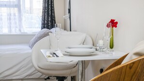 Un coin repas aménagé avec soin, avec une table dressée pour deux personnes, comprenant des assiettes, des verres et des couverts.