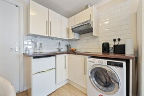 Cozinha compacta com máquina de lavar, pia e bancada.