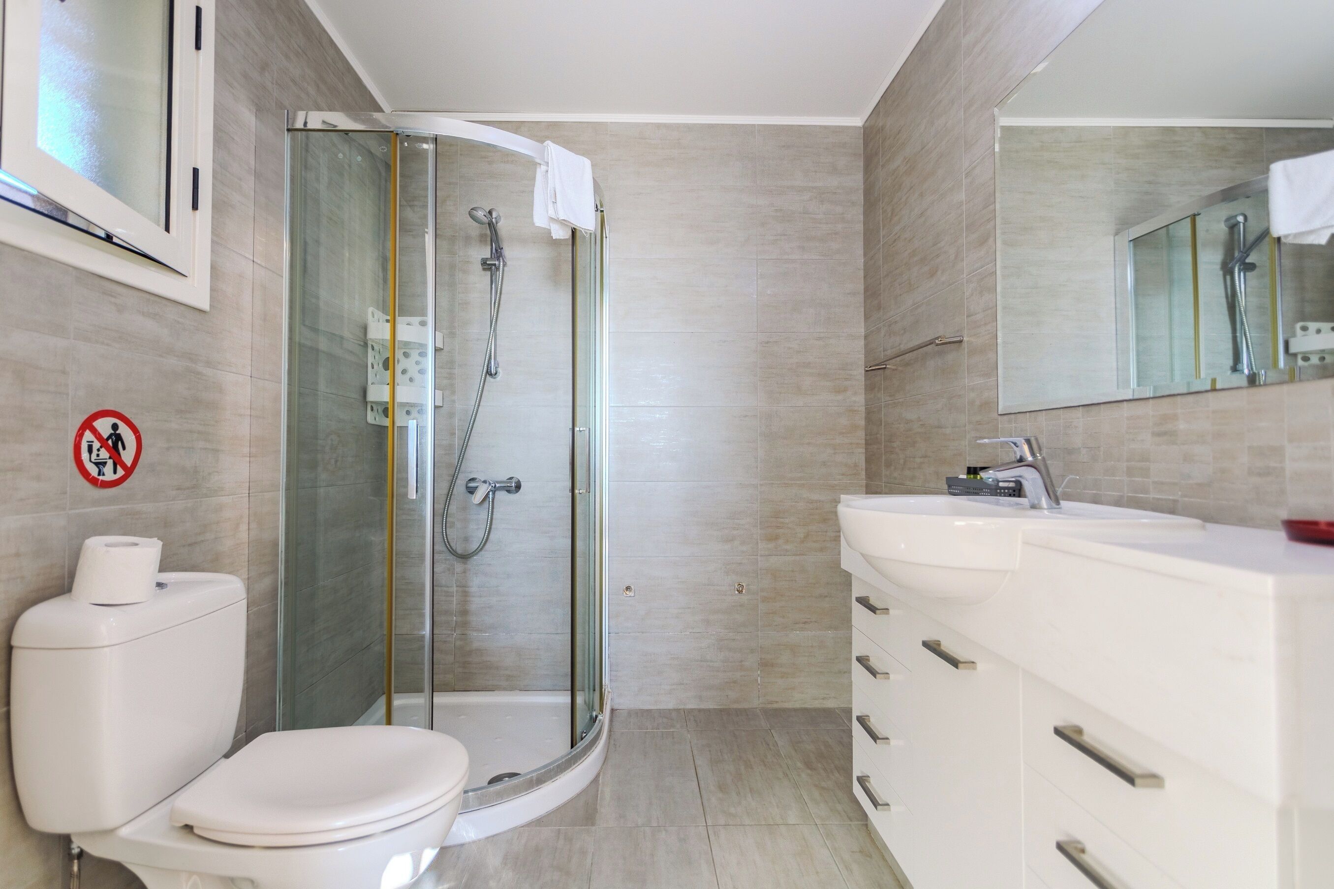 A modern bathroom with a glass-enclosed shower, a toilet, and a vanity with a mirror.