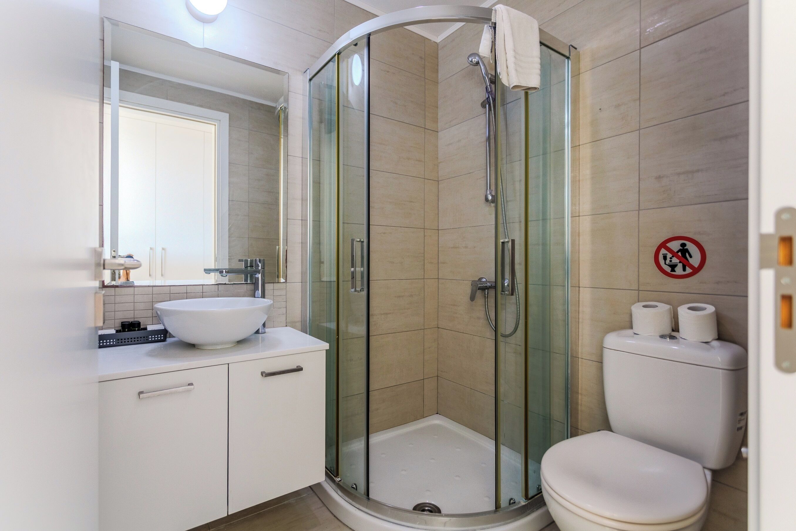 Ein modernes Badezimmer mit einer Duschkabine aus Glas, einem weißen Waschbecken und einer Toilette.
