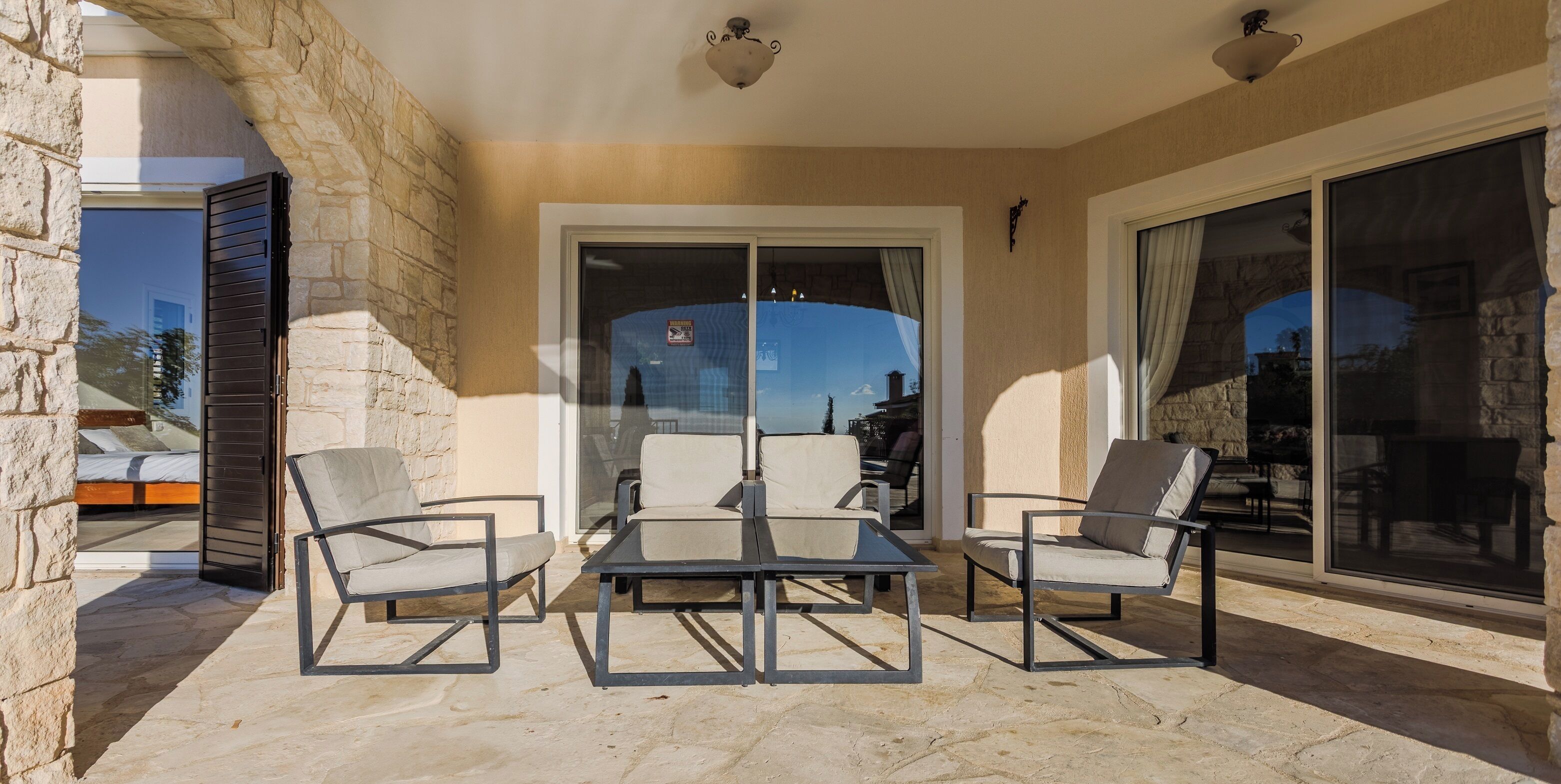 A balcony with stone walls, a glass door, and a table with chairs.