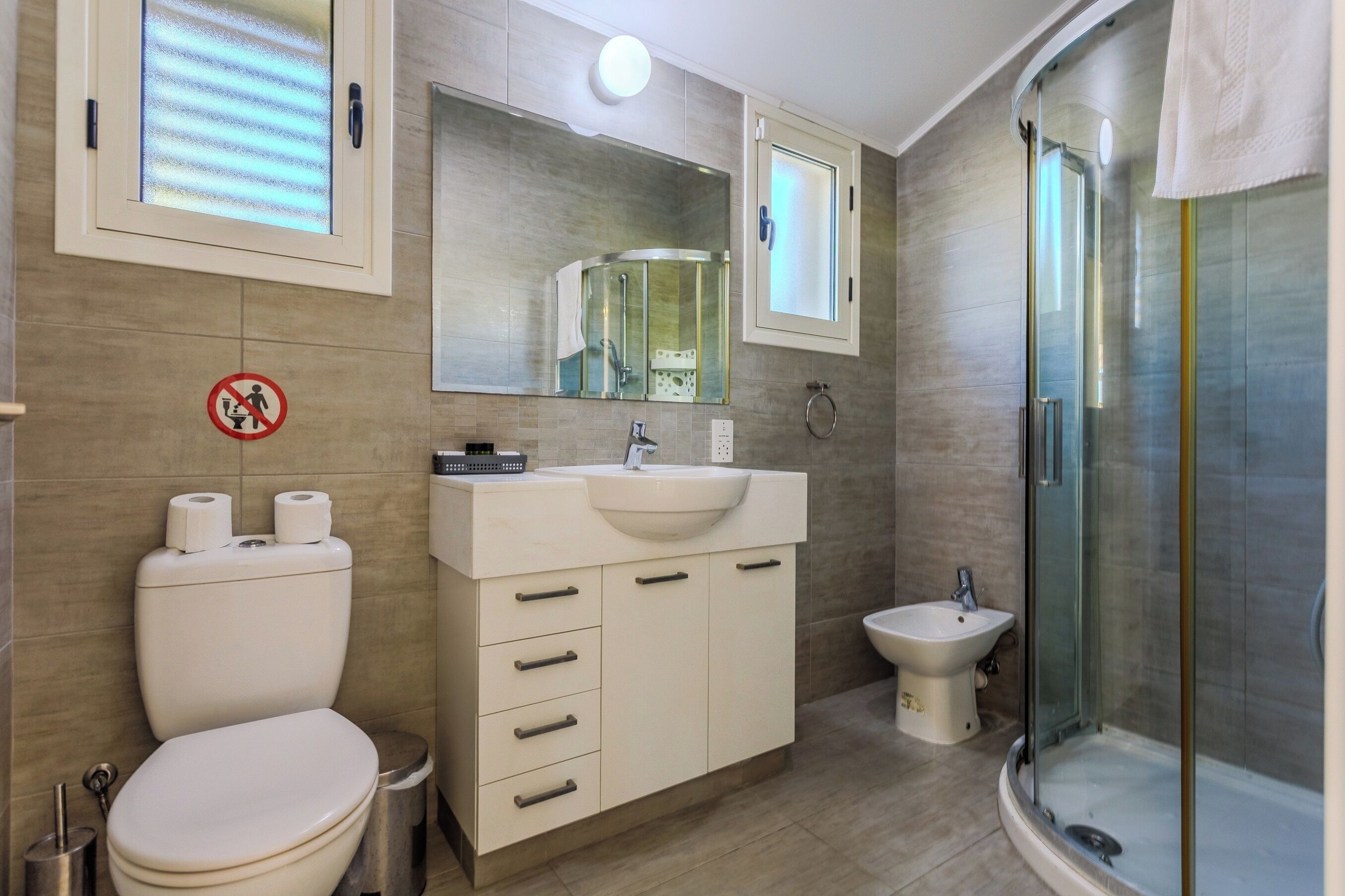 Een moderne badkamer met toilet, wastafel en douche.