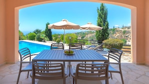 A patio with a table and chairs, a pool, and umbrellas. - Resitour - Perneri Villas (Tala)
