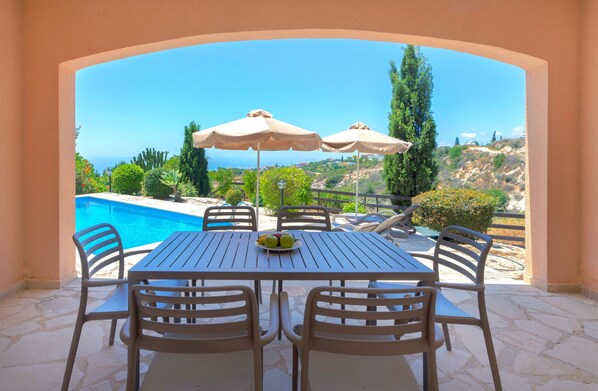 A patio with a table and chairs, a pool, and umbrellas. - Resitour - Perneri Villas (Tala)