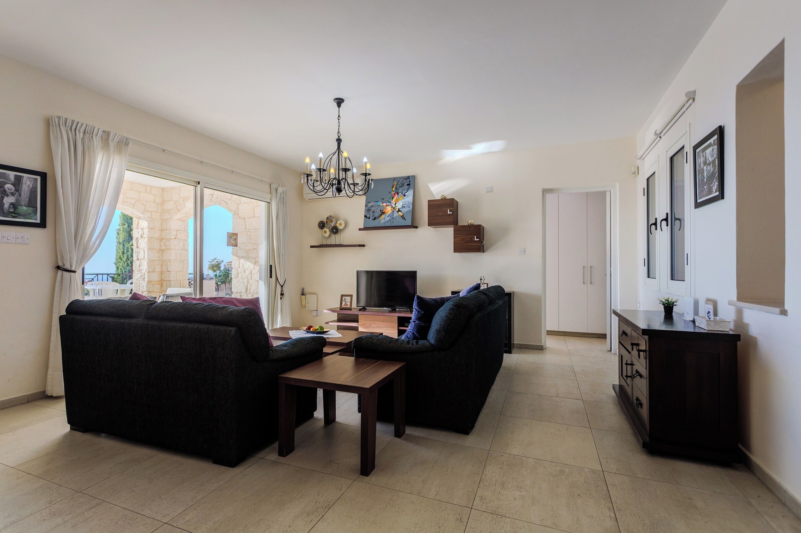 Una sala de estar con sofá, televisor, candelabro y comedor.