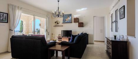 Una sala de estar con sofá, televisor, candelabro y comedor.