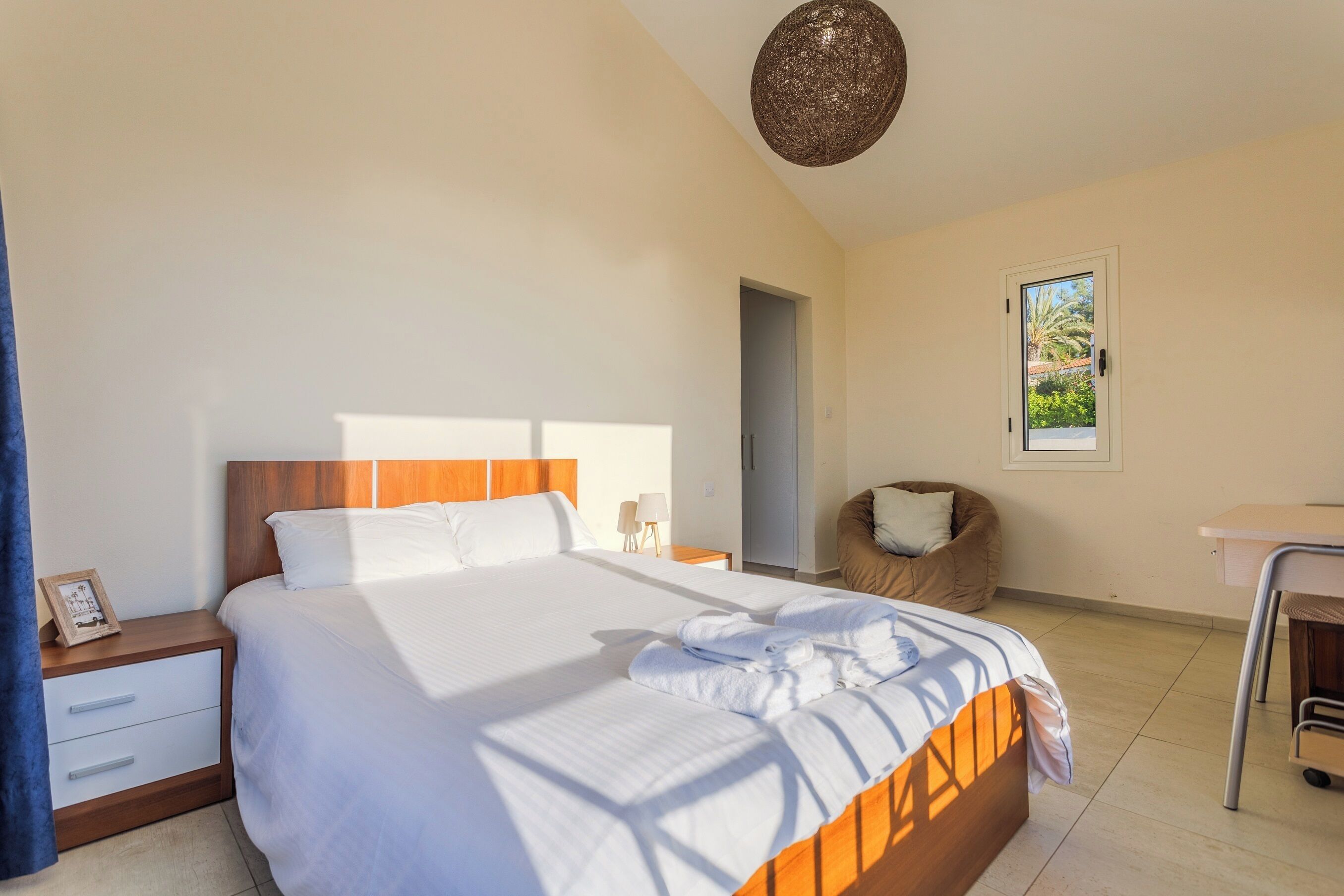 A hotel room with a bed, bedside tables, a chair, a desk, and a window with a view.