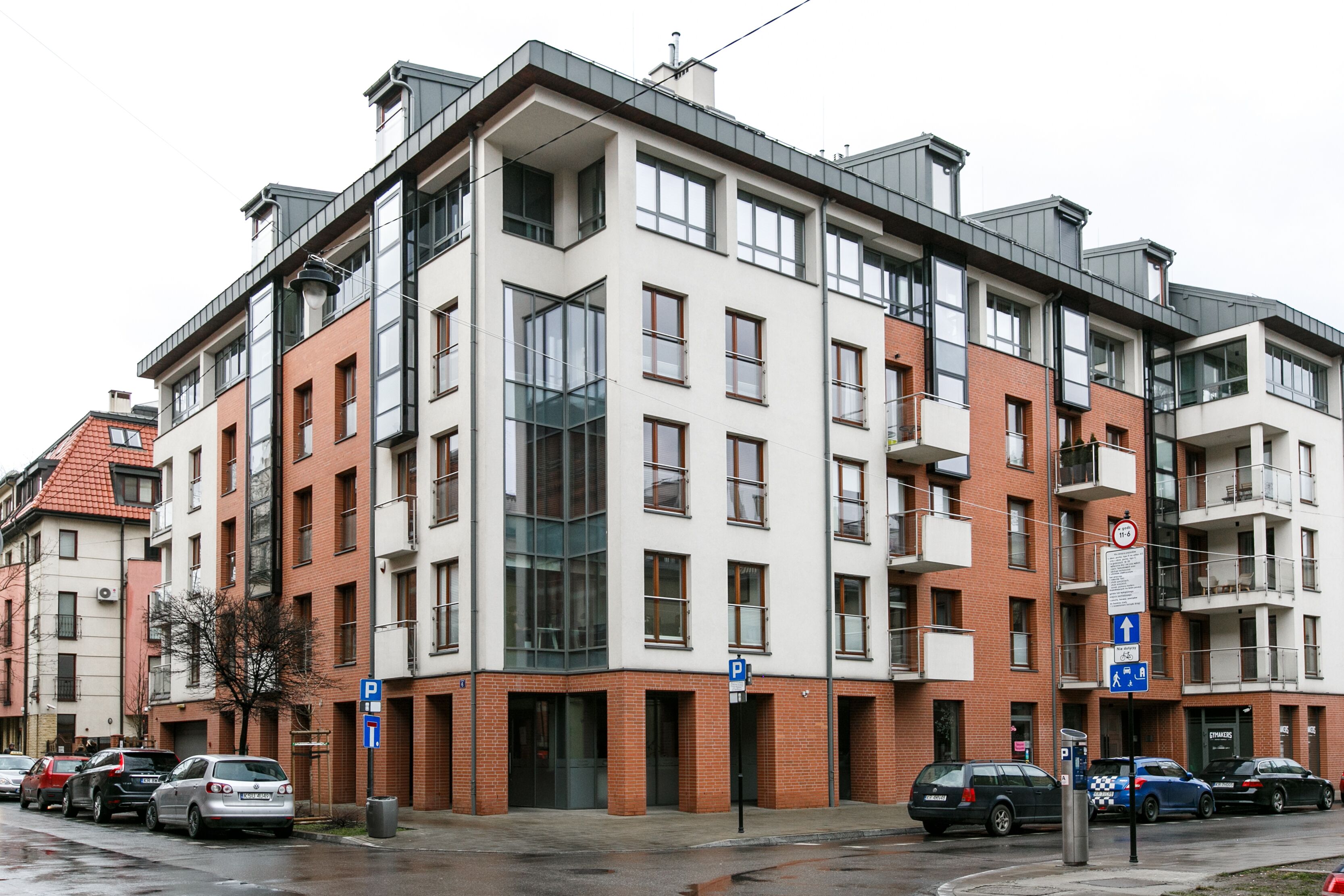 Ein mehrgeschossiges Wohngebäude mit Parkplatz davor.