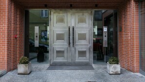 A double door entrance with a brick facade and two potted plants on either side. - Otium Old Town Harmonica (Kraków)
