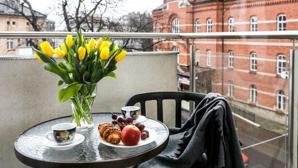 A balcony with a table set for breakfast, including a croissant, apple, grapes, and a cup of coffee. - Otium Old Town Harmonica (Kraków)