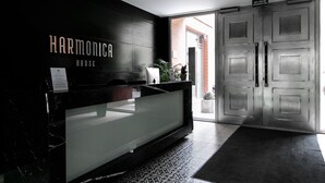 A reception area with a marble counter, a sign reading "HARMONICA HOUSE," and a door labeled "EWAUKTORIUM." - Otium Old Town Harmonica (Kraków)