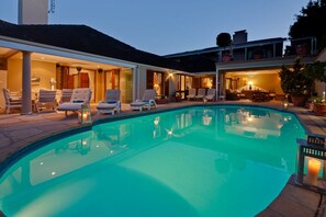 Relax by the clear pool surrounded by a contemporary setting with lounge chairs and ambient lighting.