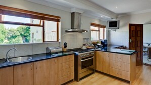 A modern kitchen with wooden cabinets, a stainless steel sink, a gas stove, and a built-in oven. - Lavender Cottage 2 Double Bedrooms 2 Bathrooms both on suite Beautiful Views (Cape Town)