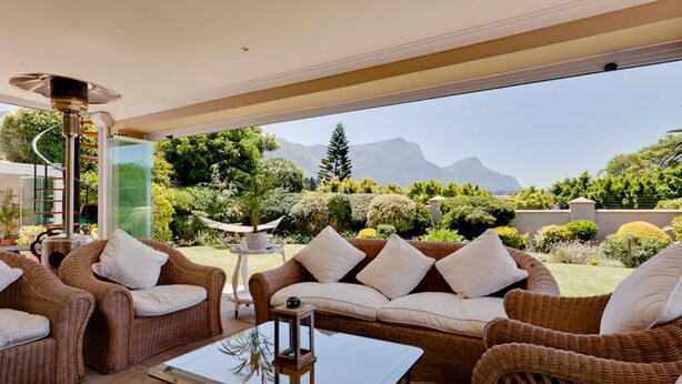 A spacious patio with wicker furniture, a glass table, and a view of a mountainous landscape. - Lavender Cottage 2 Double Bedrooms 2 Bathrooms both on suite Beautiful Views (Cape Town)