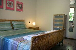 A bedroom with a bed, a nightstand, a lamp, a wardrobe, and a mirror.