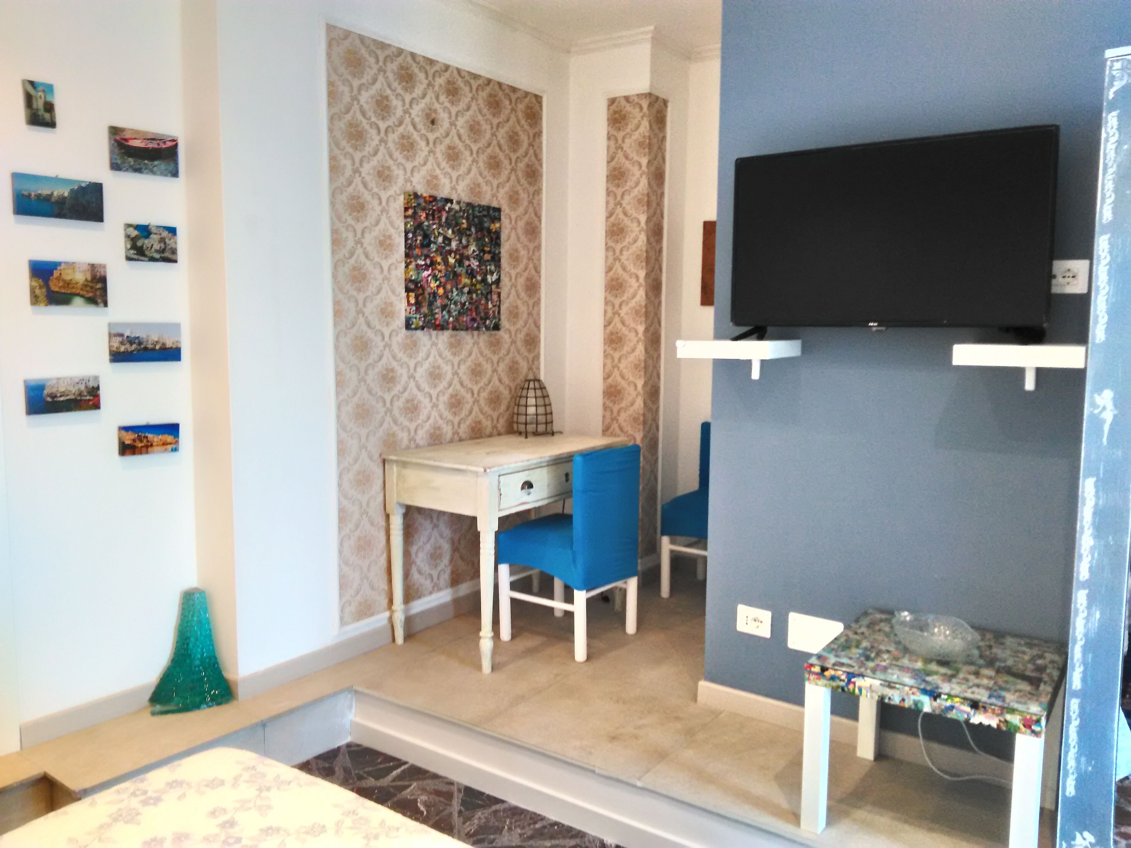 A room with a desk, chair, television, and a patterned wall.