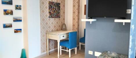 A room with a desk, chair, television, and a patterned wall.