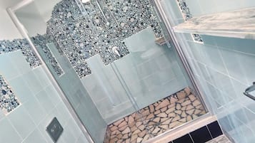 Un baño con zona de ducha, paredes con azulejos y una pared de acento de piedra.
