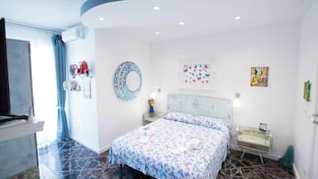 Un dormitorio con cama, espejo, ventana con cortinas, mesita de noche y una pared con una obra de arte.