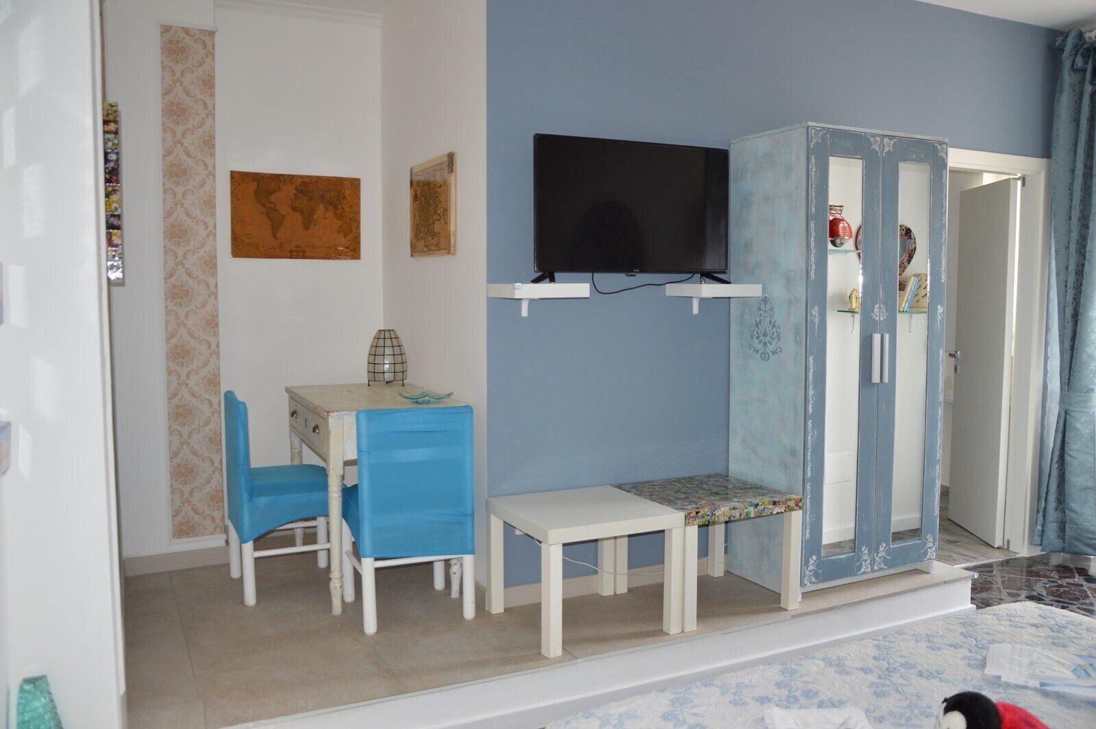A room with a desk, two chairs, a television, and a wardrobe.