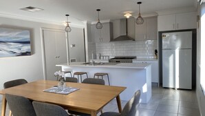 Una cocina moderna con armarios blancos, una isla central e iluminación colgante.