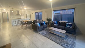 Una sala de estar moderna con un sofá, una mesa de centro y un comedor con una cocina al fondo.