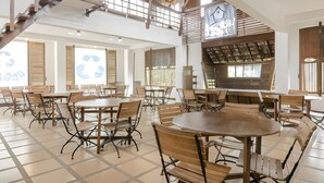 A spacious, well-lit dining area with multiple tables and chairs, a staircase, and a large window with a recycling symbol. - Kampung Lumbung Boutique Hotel (Batu)