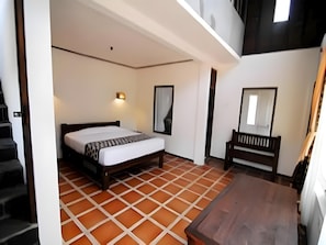 A bedroom with a bed, a bench, a wall-mounted mirror, and a staircase. - Kampung Lumbung Boutique Hotel (Batu)
