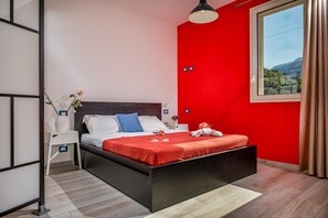 Un dormitorio moderno con estructura de cama negra, ropa de cama blanca y una pared de acento roja.