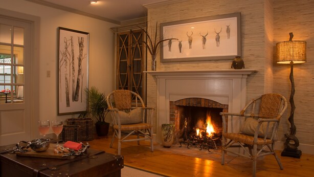 A cozy living room with a fireplace, wicker chairs, and a large framed artwork above it. - A charming 1820's farmhouse (Woodstock)