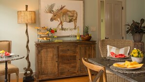 A dining area with a wooden cabinet, a table set with plates, glasses, and a decorative moose painting on the wall. - A charming 1820's farmhouse (Woodstock)