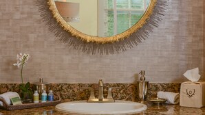 A bathroom with a round mirror, sink, and toiletries. - A charming 1820's farmhouse (Woodstock)