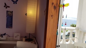 A room with a bed, a bedside table, a lamp, butterfly wall decals, and a view of the sea through a balcony. - Room-the Magic Dragonfly! (Candelaria)