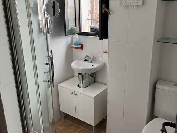 A compact bathroom with a white sink, a mirror, and a toilet. - House with terrace and great views (Albuñuelas)
