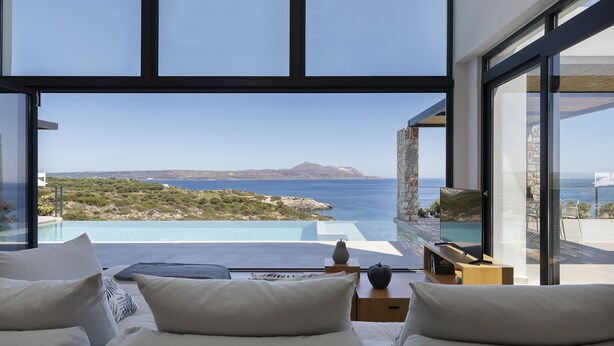 Un dormitorio moderno con un ventanal grande que da a una piscina y al mar.