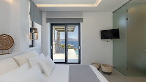 Un dormitorio con cama, televisión y vista al mar a través de una puerta corrediza.