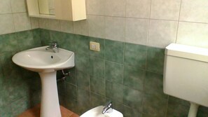 Ein Badezimmer mit einem weißen Waschbecken, grünen Fliesenwänden und einer weißen Toilette.