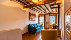 A cozy living room with a wooden ceiling, a blue sofa, a yellow armchair, and a painting on the wall. - Cosy restored rural house (Albuñuelas)