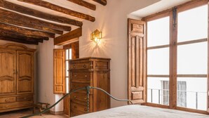 A bedroom with a large bed, wooden wardrobe, and a window with a view. - Cosy restored rural house (Albuñuelas)