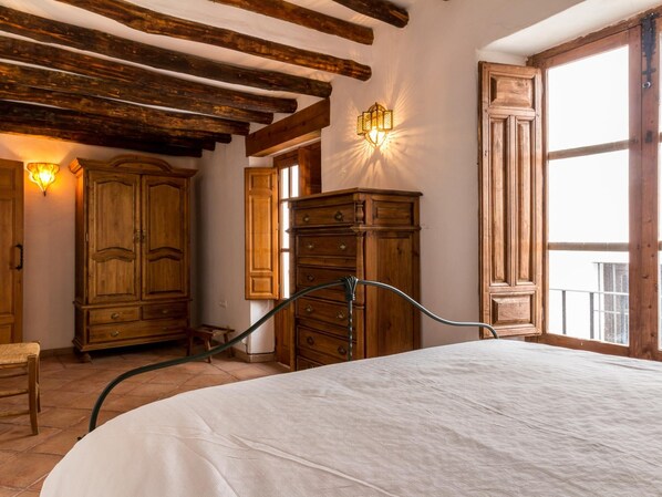 A bedroom with a large bed, wooden wardrobe, and a window with a view. - Cosy restored rural house (Albuñuelas)