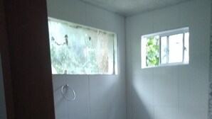 Une salle de bain avec des toilettes, une petite fenêtre et un meuble en bois.