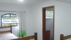 Une pièce avec deux lits superposés en bois, une fenêtre avec des rideaux, une petite commode en bois et un miroir au mur.