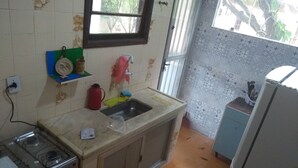 Une cuisine de taille réduite équipée d’une cuisinière à gaz, d’un évier et d’un réfrigérateur.