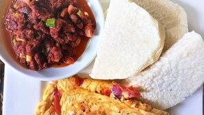 A plate with a bowl of chili, two pieces of white bread, and scrambled eggs. - City Crown Hotels Limited (Port Harcourt)