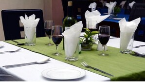 A table set for dining with wine glasses, a bottle, and a green tablecloth. - City Crown Hotels Limited (Port Harcourt)
